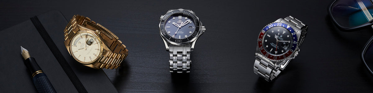 Gold Rolex, stainless steel Omega and Rolex GMT watches on a dark desktop